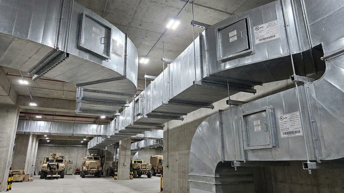 Al Udeid Air Base — galvanized rectangular ductwork with access panels suspended in a vehicle hangar